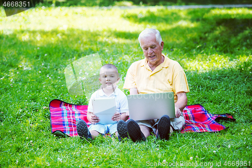 Image of grandfather and child using laptop