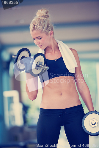 Image of lifting some weights and working on her biceps in a gym