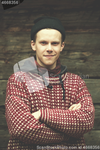 Image of young hipster in front of wooden house