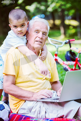 Image of grandfather and child using laptop