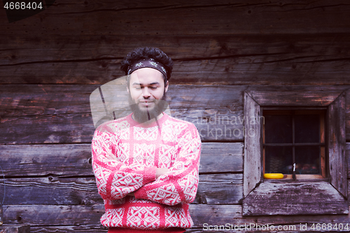 Image of portrait of young hipster in front of wooden house