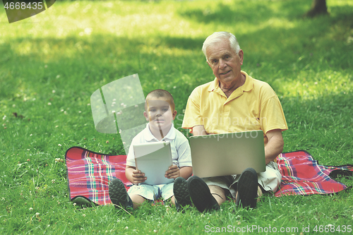 Image of grandfather and child using laptop