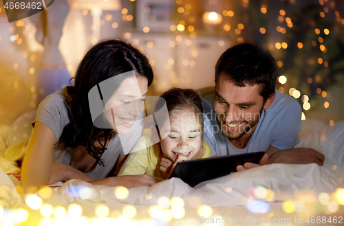 Image of family with tablet pc in bed at night at home