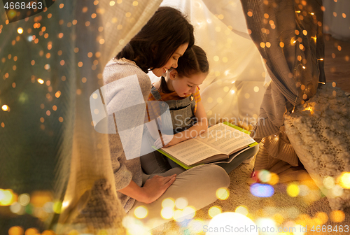 Image of happy family reading book in kids tent at home