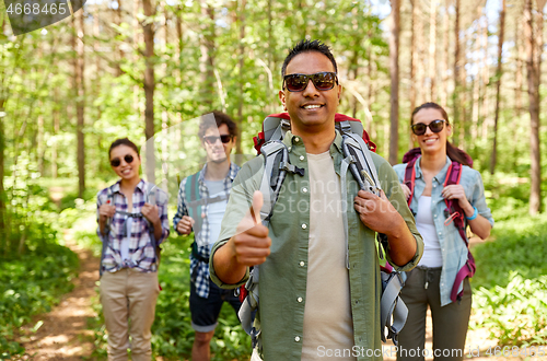 Image of friends with backpacks showing thumbs up in forest