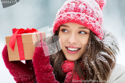 Image of happy young woman with christmas gift in winter