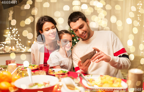 Image of family with smartphone having christmas dinner
