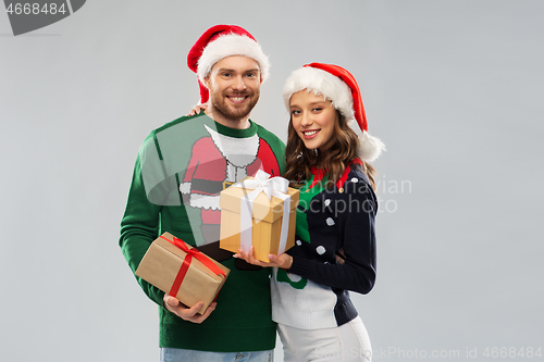 Image of happy couple in christmas sweaters with gifts