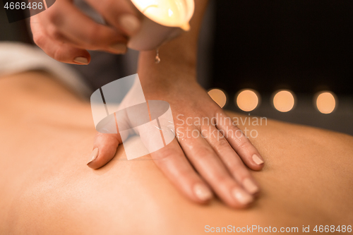 Image of back massage with hot oil candle at spa