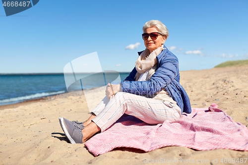 Image of happy senior woman in jacket on beach