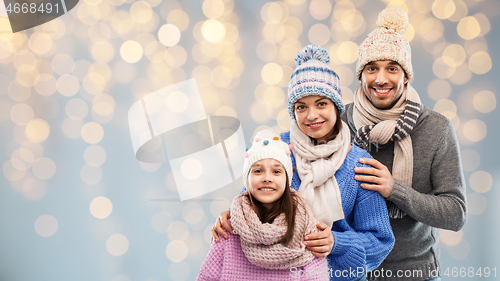 Image of family in winter clothes over christmas lights