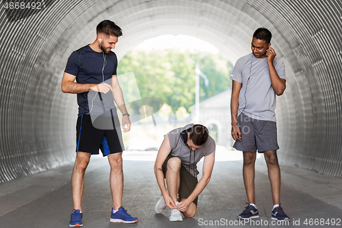 Image of male friends with earphones training outdoors