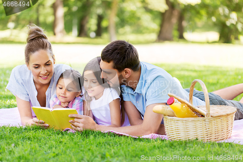 Image of family reading book on picnic in summer park