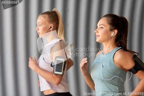 Image of young women with earphones and smartphones running