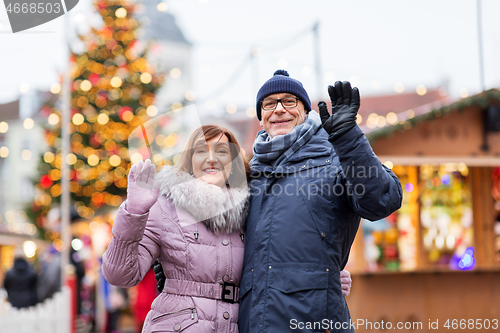Image of senior couple waving hands at christmas market