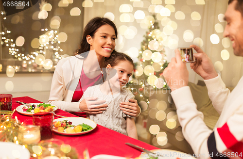 Image of happy family taking picture at christmas dinner