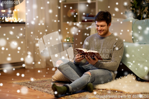 Image of happy young man reading book at home