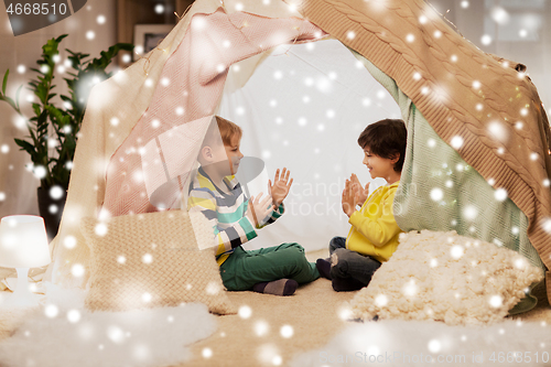 Image of boys playing clapping game in kids tent at home