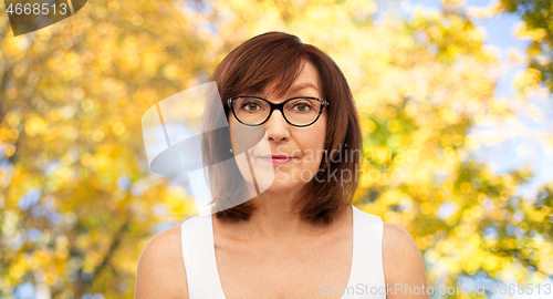 Image of portrait of senior woman in glasses over autumn