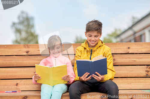Image of school children reading books sitting on bench