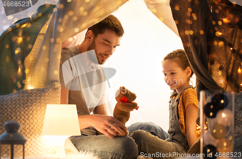 Image of happy family playing with toy in kids tent at home