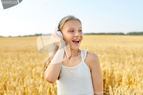 Image of happy girl in headphones on cereal field in summer