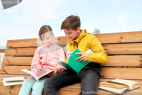 Image of school children with notebooks sitting on bench