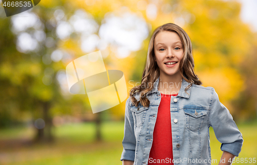 Image of happy teenage girl in denim jacket in autumn park