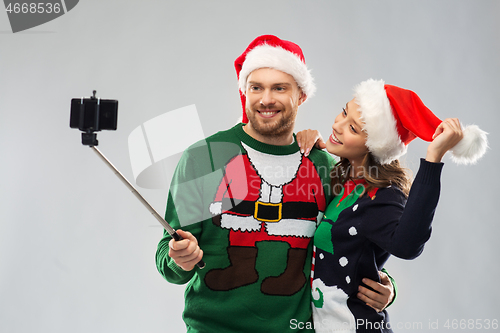 Image of happy couple in christmas sweaters taking selfie