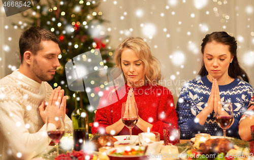 Image of friends praying before christmas dinner at home