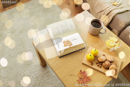 Image of book, lemon, tea and cookies on table at home