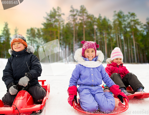 Image of happy little kids sliding down on sleds in winter