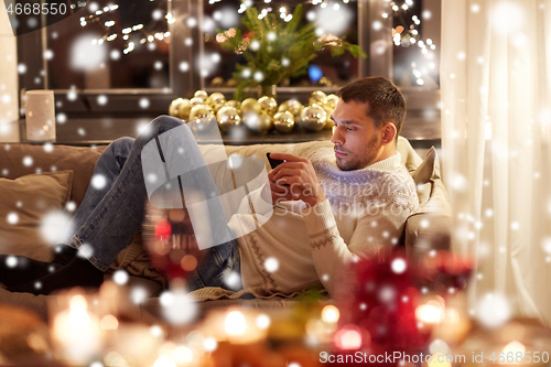 Image of man with smartphone at home for christmas