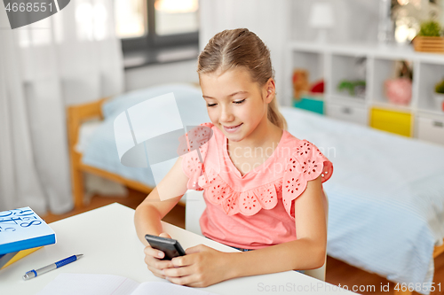 Image of happy student girl using smartphone at home