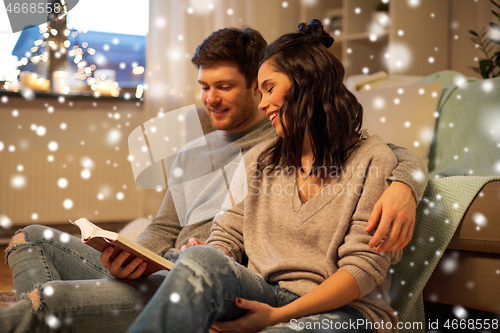 Image of happy couple reading book at home