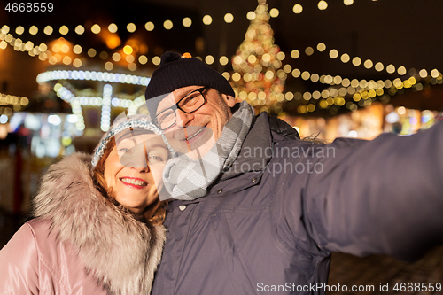 Image of senior couple taking selfie at christmas market