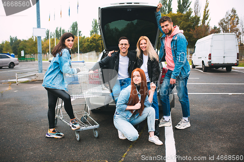 Image of Group of four young diverse friends in jeanse outfit look carefree, young and happy on city\'s streets