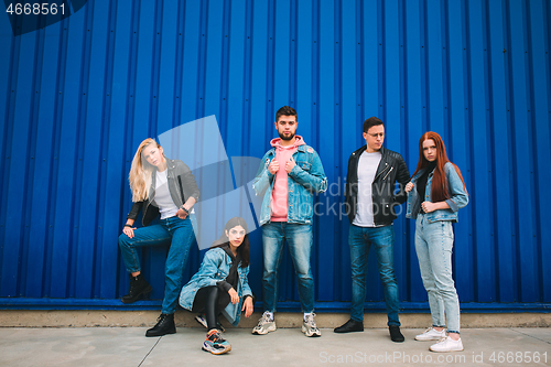 Image of Group of four young diverse friends in jeanse outfit look carefree, young and happy on city\'s streets