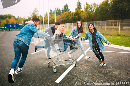 Image of Group of four young diverse friends in jeanse outfit look carefree, young and happy on city\'s streets