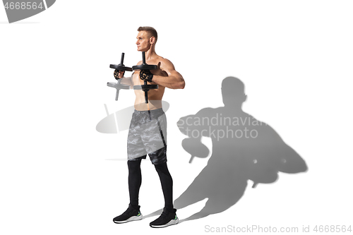 Image of Beautiful young male athlete practicing on white studio background with shadows