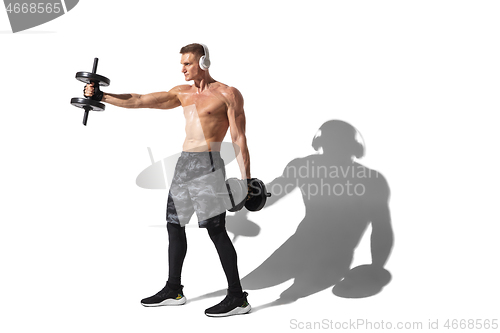 Image of Beautiful young male athlete practicing on white studio background with shadows