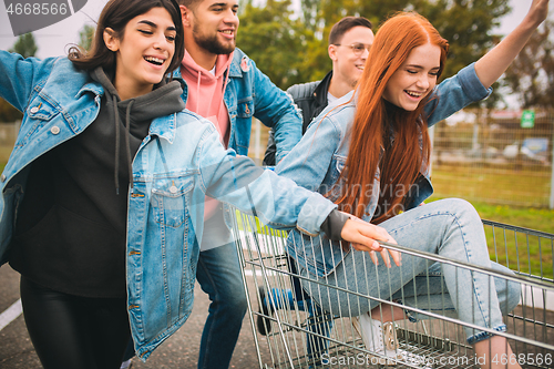 Image of Group of four young diverse friends in jeanse outfit look carefree, young and happy on city\'s streets