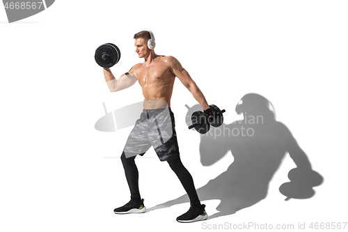 Image of Beautiful young male athlete practicing on white studio background with shadows