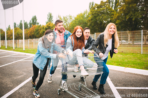 Image of Group of four young diverse friends in jeanse outfit look carefree, young and happy on city\'s streets