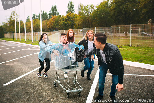 Image of Group of four young diverse friends in jeanse outfit look carefree, young and happy on city\'s streets