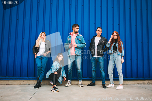 Image of Group of four young diverse friends in jeanse outfit look carefree, young and happy on city\'s streets