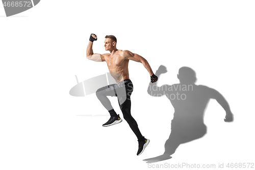 Image of Beautiful young male athlete practicing on white studio background with shadows