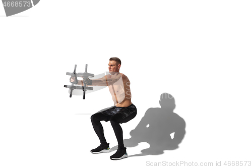 Image of Beautiful young male athlete practicing on white studio background with shadows