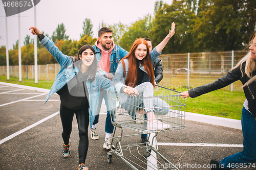 Image of Group of four young diverse friends in jeanse outfit look carefree, young and happy on city\'s streets