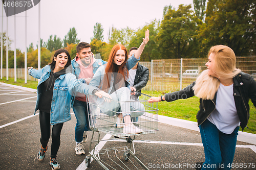 Image of Group of four young diverse friends in jeanse outfit look carefree, young and happy on city\'s streets